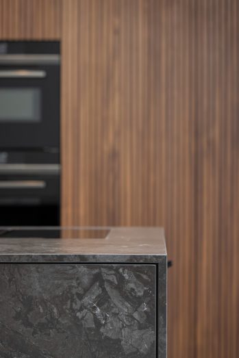 detailfoto donker kookeiland met houten kastenwand