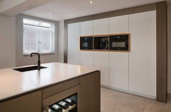 Strakke moderne keuken met witte kastenwand en bronzen details
