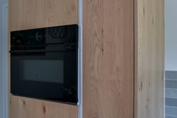 Hoge eiken fineer kast met zwart apparatuur