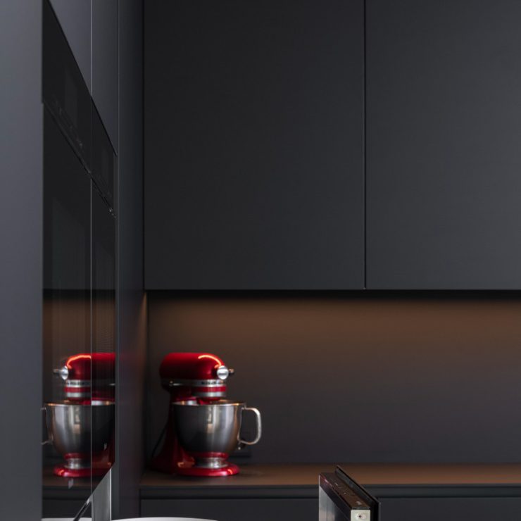 Moderne mat zwarte Mereno keuken met RVS eiland met warmhoudlade